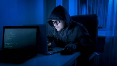 Erkek hacker geceleri evden bilgisayarla çalışıyor.
