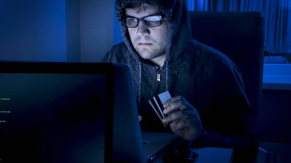 Portret hakera z kartami kredytowymi pracującymi w nocy na komputerze — Zdjęcie stockowe