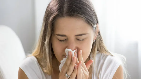 Portret van zieke jonge vrouw niezen en snuit haar neus in papieren weefsel — Stockfoto