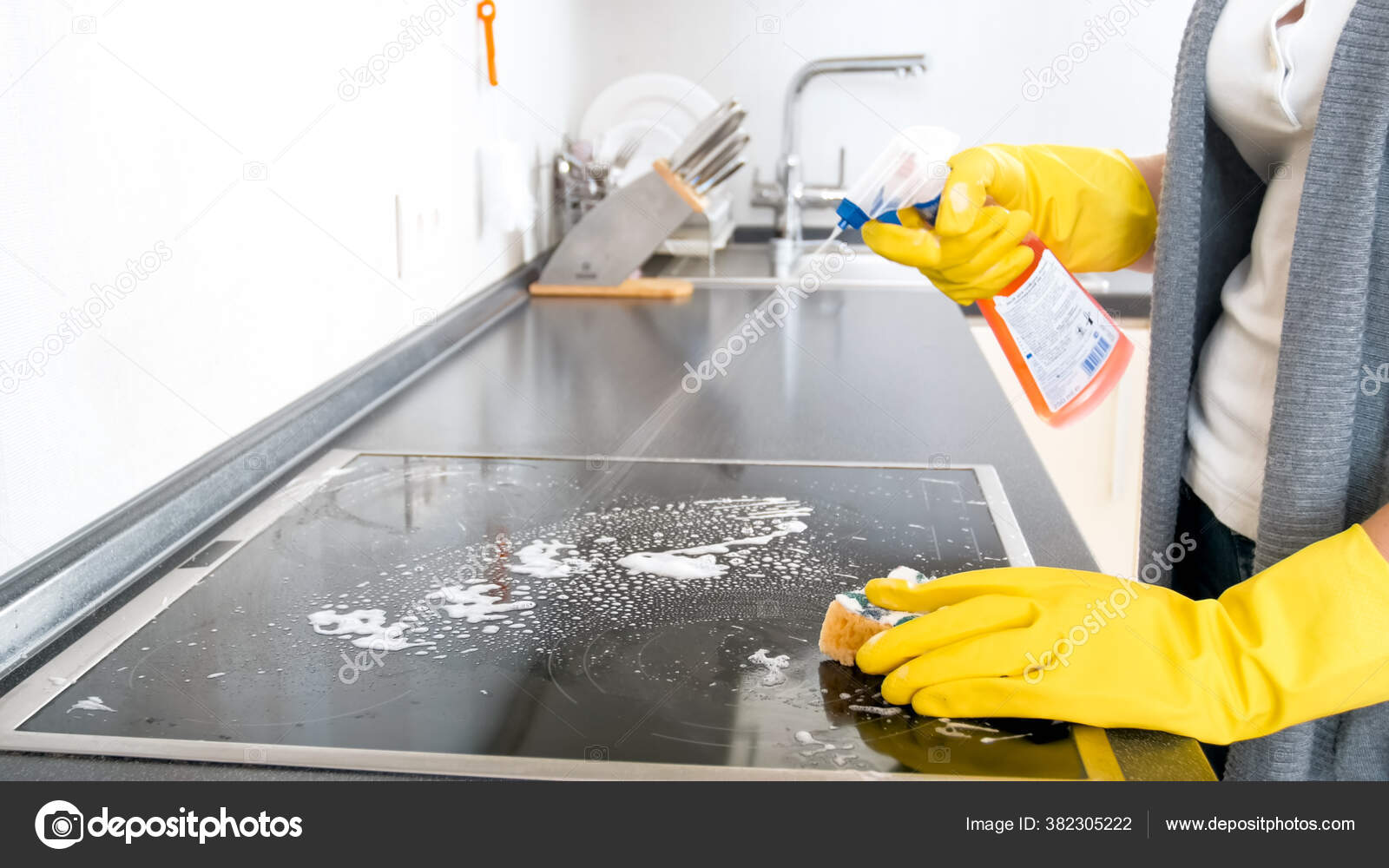 Young housewife using detergent spray for cleaning glass electric stove