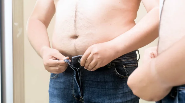 Mann mit dickem Bauch trägt enge, kleine Hosen in der Umkleidekabine. Konzept von männlichem Übergewicht, Gewichtsverlust und Diät — Stockfoto