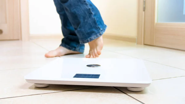 Junge, barfüßige Frau, die zu Hause mit digitalen Gewichten am Boden steht. Konzept von Übergewicht, Gewichtsverlust und Diät — Stockfoto