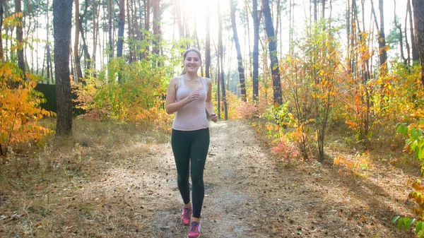 Happy smiling woman in leggings running in forest on sunny day — Stock Photo, Image