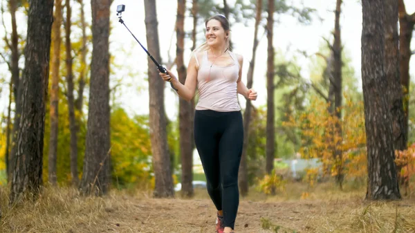 Sorridente giovane donna fare foto selfie su smartphone durante la corsa nella foresta — Foto Stock