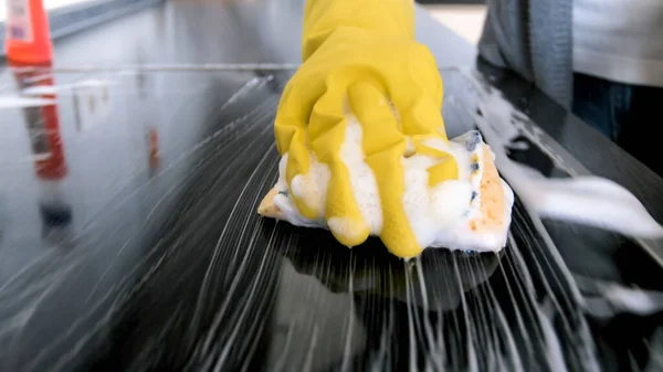 Närbild iamge av yougn woamn i gummihandskar tvätta elektrisk spis med svamp och tvättmedel — Stockfoto