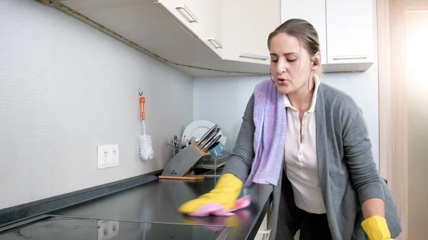 Portret van een vrolijke glimlachende vrouw die muziek zingt en luistert tijdens het schoonmaken en wassen van de keuken — Stockfoto