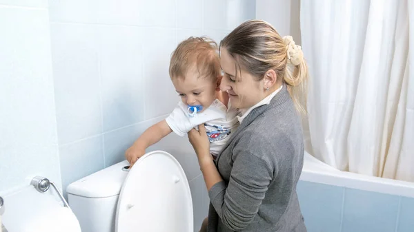 小さな幼児男の子フラッシング水でトイレに若いです母 — ストック写真