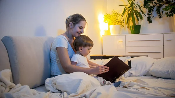 Молодая мать читает сказки на ночь своему маленькому сыну — стоковое фото