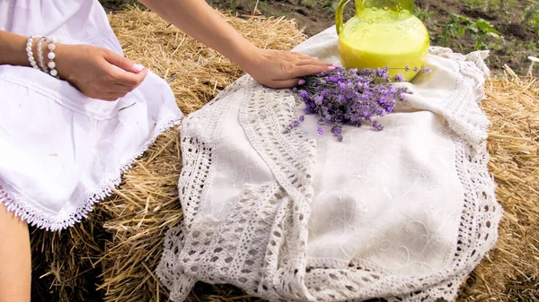 Närbild bild av kvinnan sitter på höstack och håller lavendel blommor bukett — Stockfoto