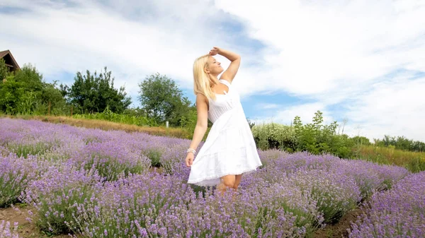 하얀 드레스를 입은 아름다운 웃는 여인 이 프로방스의 큰 라벤데 들판을 바라보고 있다 — 스톡 사진