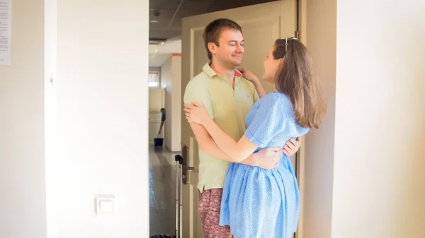 Glada leende par kramas och titta på varandra efter att ha kommit till hotellet på sommarsemester — Stockfoto