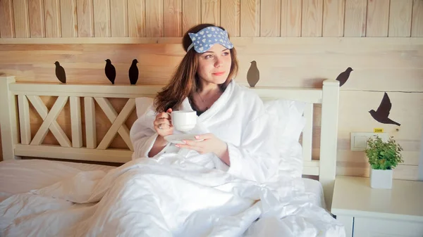 Banyodaki genç kadının portresi otel odasında uzanıyor ve kahve içiyor. — Stok fotoğraf