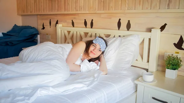 Retrato de una linda mujer sonriente acostada en la cama en la habitación de hotel por la mañana — Foto de Stock