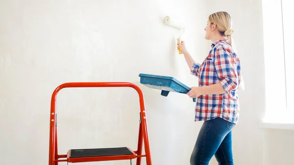 Красивая молодая женщина в клетчатой рубашке делает ремонт дома — стоковое фото