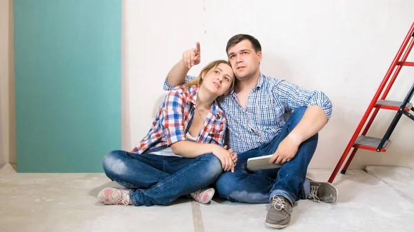 Feliz homem sorridente com esposa escolhendo cor de pintura de parede em sua nova casa em renovação — Fotografia de Stock
