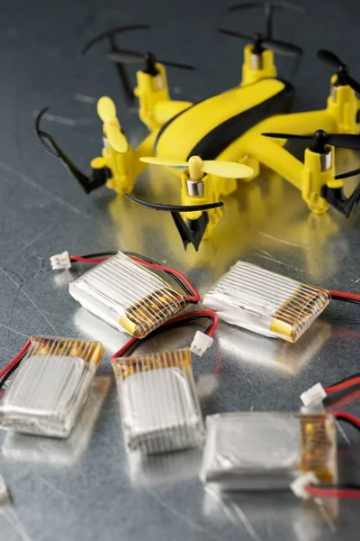 Yellow drone and batteries on a metal table.