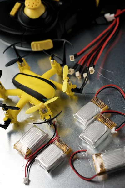 Yellow drone and batteries on a metal table.