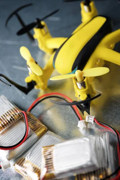 Yellow drone and batteries on a metal table.