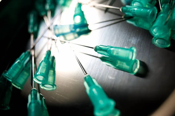 Group of needles for syringe on a metal tray.