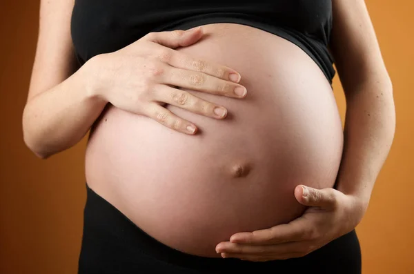 Zwangere Vrouw Strelen Haar Buik Met Oranje Achtergrond — Stockfoto