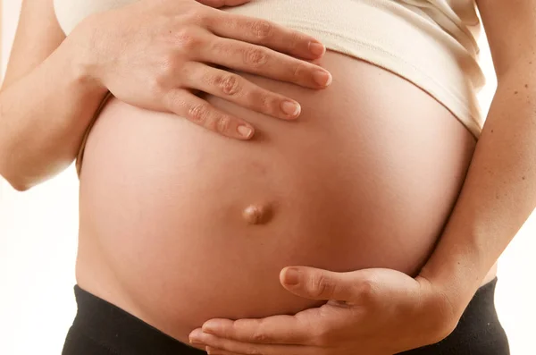 妊娠中の女性の白い背景を持つ彼女の腹を愛撫 — ストック写真