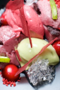 Çilekli ve şam fıstıklı dondurma ve siyah kasede kirazlar..