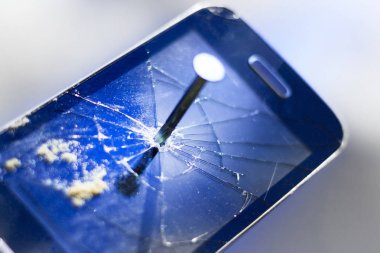 Bir çivi eski bir telefonu, bu yumruk attı. Arka planda yeni bir telefon.