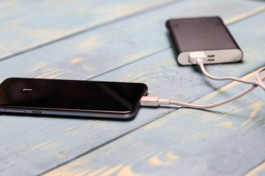 cep telefonu ve bir ahşap antika arka plan üzerinde şarj etmek için yedek pil.