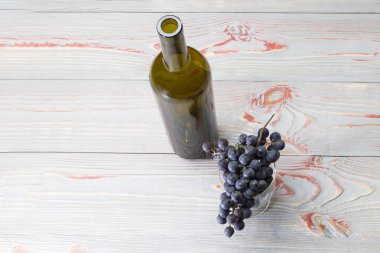 bir şişe ve bir bardakta mı karanlık üzüm, ahşap arka plan gri bir arka plan karşı bir dalı