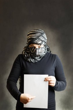 Güzel, siyah peçe gri bir ağaç üzerinde kapalı bir suratla kız. Bir parça kağıt elinde. Kopya alanı