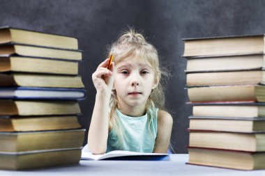 Kız öğrenci, bir yığın kitap ve bir kalem ile sarışın kız bir defterde yazar. Orada tonlama.