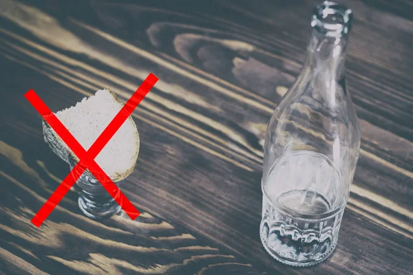 Een glas van zuivere alcohol, een fles en een stukje brood en kaas op een houten achtergrond. een glas en daarop een Rode Kruis. concept van het stoppen drinken. Er is toning — Stockfoto