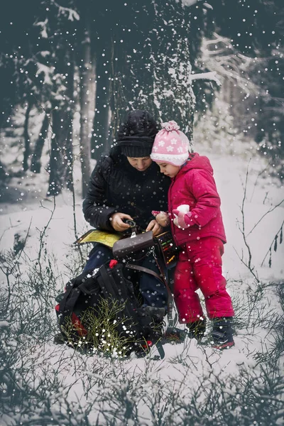 it is cold in winter, it is snowing. Girl and daughter, with a compass and odometer in his hand paves the route. have toning. Girls traveling in the forest.