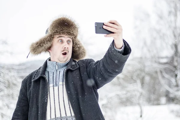 Młody Człowiek Jest Zaskoczony Aparat Sprawia Selfie Lesie Mroźną Zimę — Zdjęcie stockowe