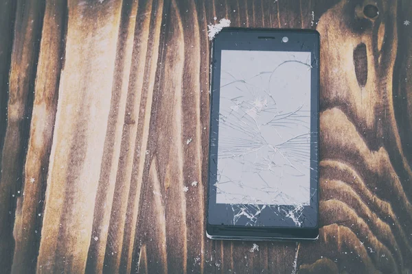 broken mobile phone on a wooden background. Mobile phone repair. there is toning.