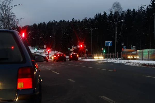 Winter, a lot of snow, cold. Back view. brake lights are on the car. Red light on a setafor. Evening, dark, bad, seeing the road.