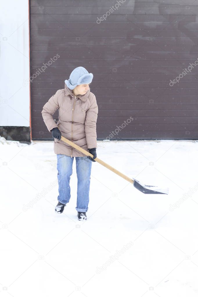 Winter is a lot of snow. A young girl, cleans, proud of doing the big shovel work.
