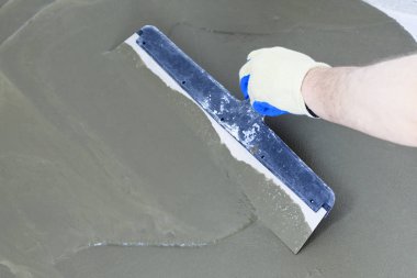 concrete floor. on it fly out to even out the horizon. close-up. worker with a spatula to drive the liquid across the floor. clipart