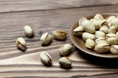 Kavrulmuş fıstık kil tabakta. eski ahşap arka plan.