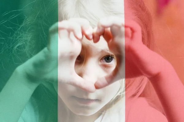 Flicka med vitt hår gör ett hjärta och ser in i den. mot bakgrund av den italienska flaggan. Lär dig italienska språk Online utbildning koncept — Stockfoto