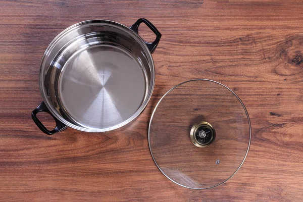 Une casserole sur fond en bois. il y a un couvercle en verre . — Photo