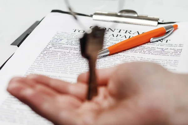Este es un contrato para la compra de un apartamento. Hay dos llaves para ellos. bolígrafo para la firma. la mano no es una niña toma las llaves . — Foto de Stock