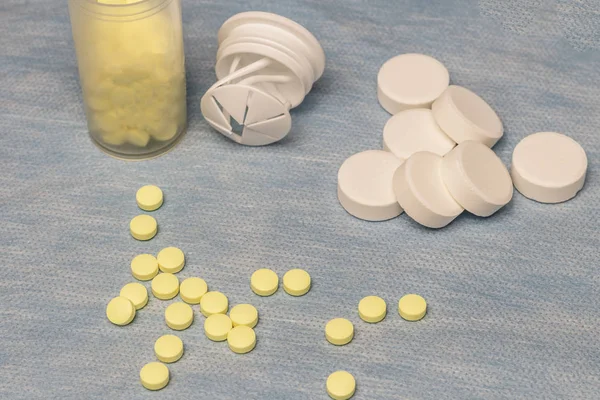 På en blå bakgrund är små gula tabletter och stora vita sådana. Det är toning. — Stockfoto