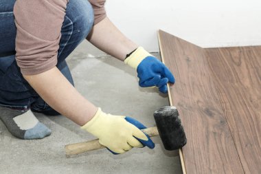 Mavi eldiven yöneticisinde döşeme yapar. floorboard. bir düzeyi vardır. ve lastik çekiç.