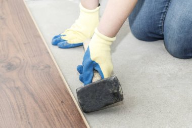 Mavi eldiven yöneticisinde döşeme yapar. floorboard. bir düzeyi vardır. ve lastik çekiç.