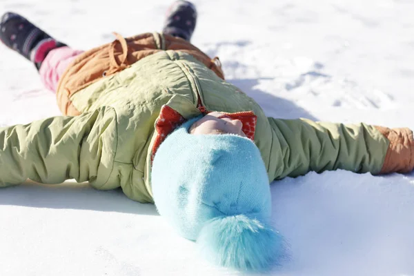 La niña dibuja en el ángel de la nieve. profundidad de campo poco profunda . —  Fotos de Stock