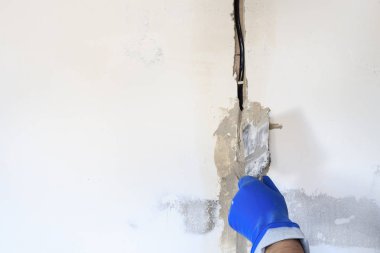 Teknik delik bir elektrik teli var. duvar beyazdır. Kablonun bir spatula ve harç ile Master kapsar