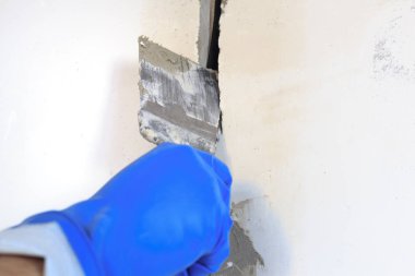 Teknik delik bir elektrik teli var. duvar beyazdır. Kablonun bir spatula ve harç ile Master kapsar