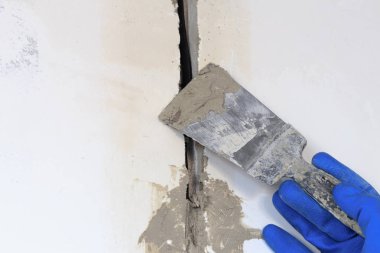 Teknik delik bir elektrik teli var. duvar beyazdır. Kablonun bir spatula ve harç ile Master kapsar