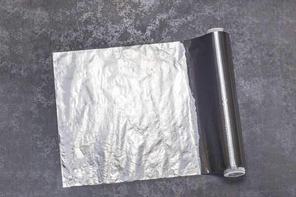 фольга для приготовления пищи. лежит на столе. Она развернута и немного перегружена.
.